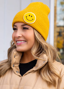 Mustard cuffed knit beanie with smiley face patch Women's fitted beanie hat with a smiley face graphic on the front of the hat