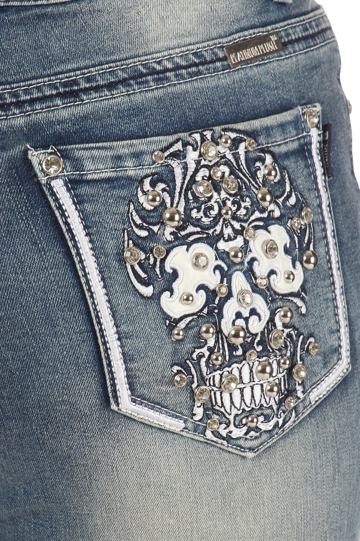 Gorgeously designed skull candy embroidery with leather and border detailing embellished in rhinestones on a 5 pocket, boot-cut